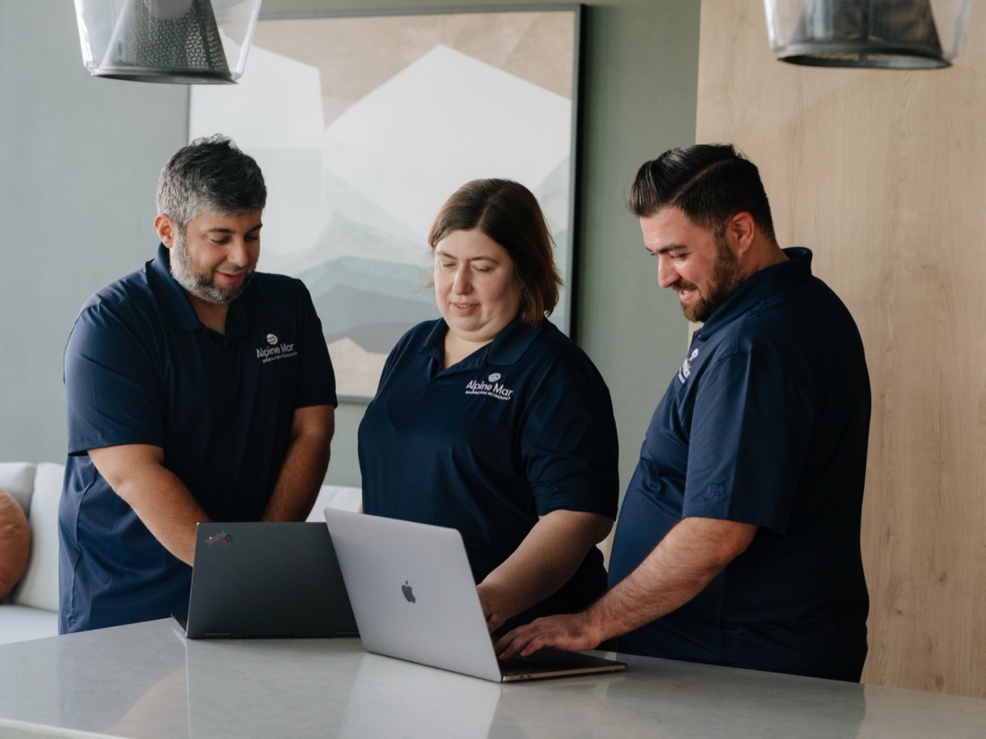 Alpine Mar IT team collaborating over laptops in the office
